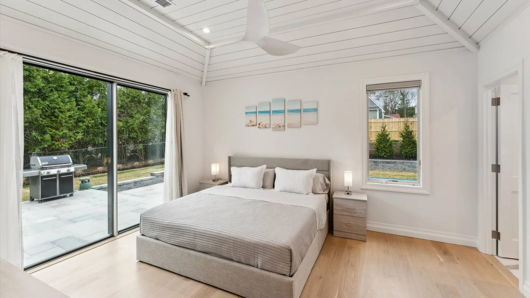 A bright bedroom with a large bed and sliding glass doors opening to a patio.