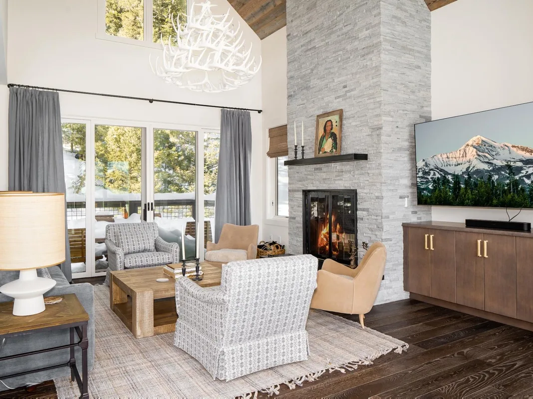 Una sala luminosa con asientos alrededor de una chimenea de piedra y un televisor.