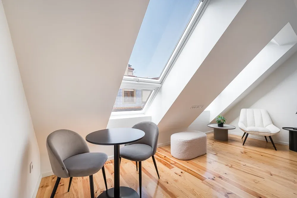A bright attic sitting area with seating beside a large skylight.