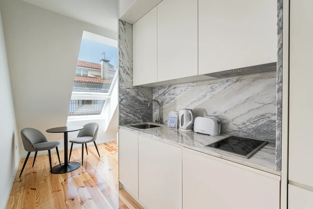 A compact kitchen with a dining table beside a slanted window.