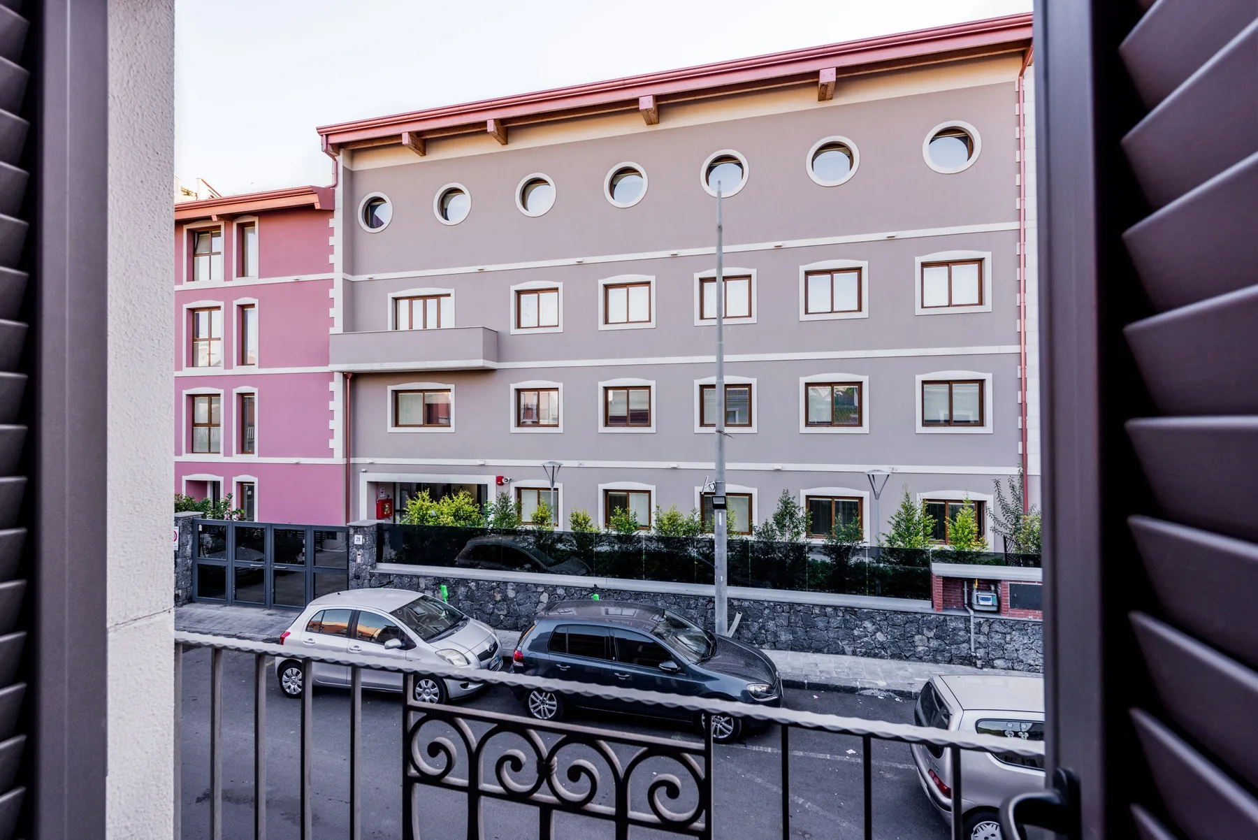 A view of a pink and gray building from a window overlooking the street.