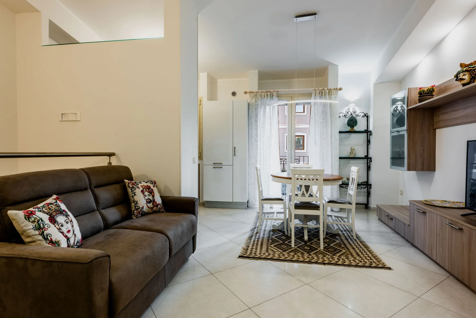 A bright living and dining area with seating, a table, and a window.