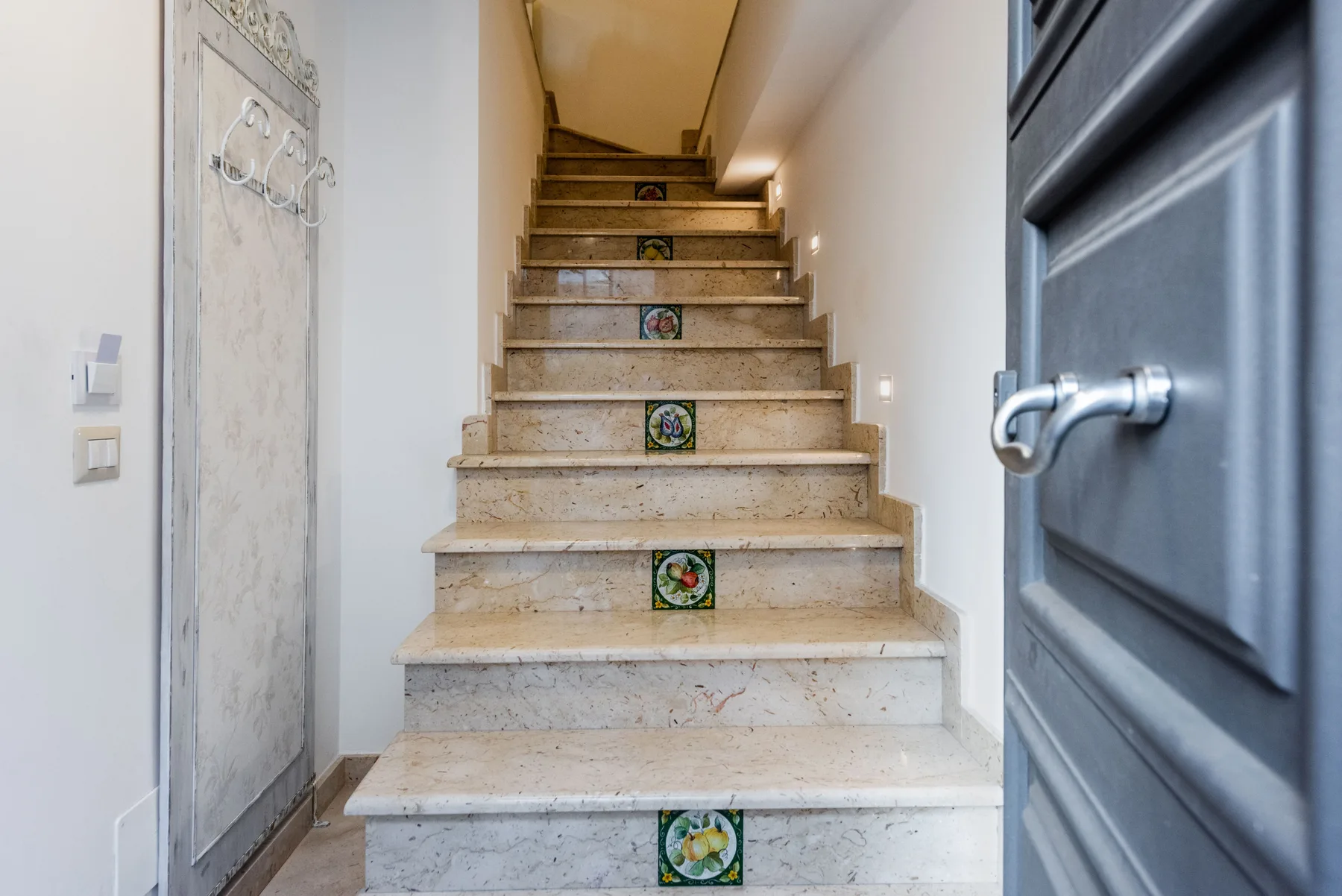 A stone staircase with decorative tile accents leads upward through a narrow interior.