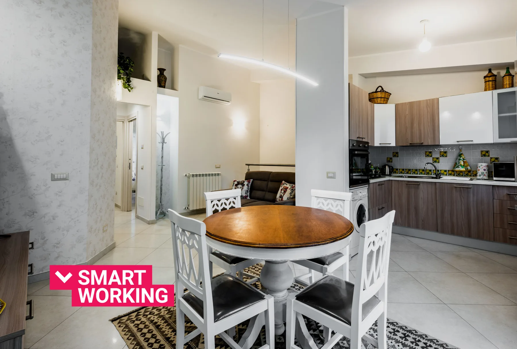 A dining area with a round table and an open kitchen in the background.