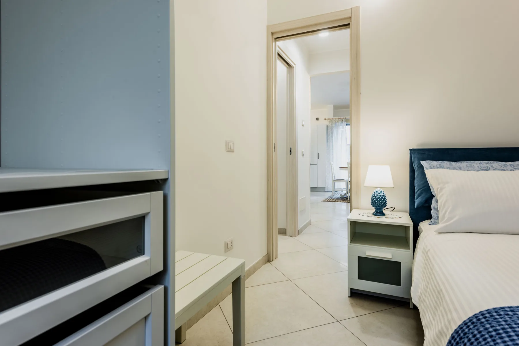 A bedroom with a bed and bedside table, facing an open doorway.