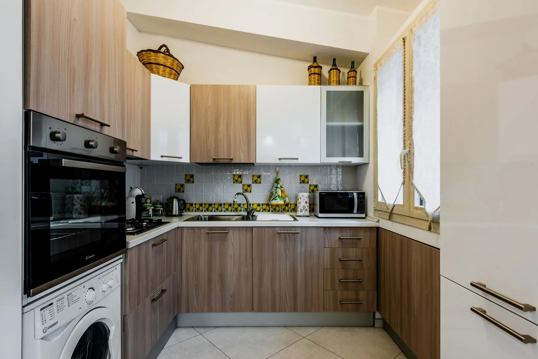 Una cocina compacta con gabinetes en tonos de madera y un salpicadero de azulejos.