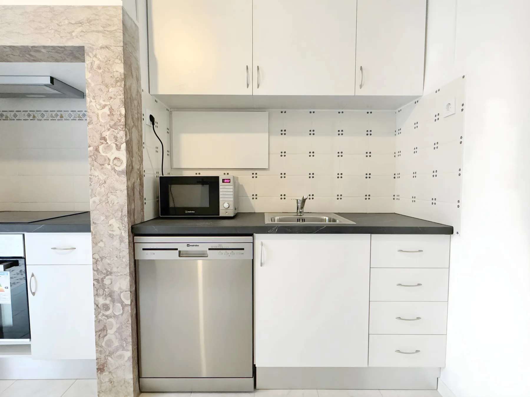 A compact kitchen with white cabinets, a countertop, and a sink.