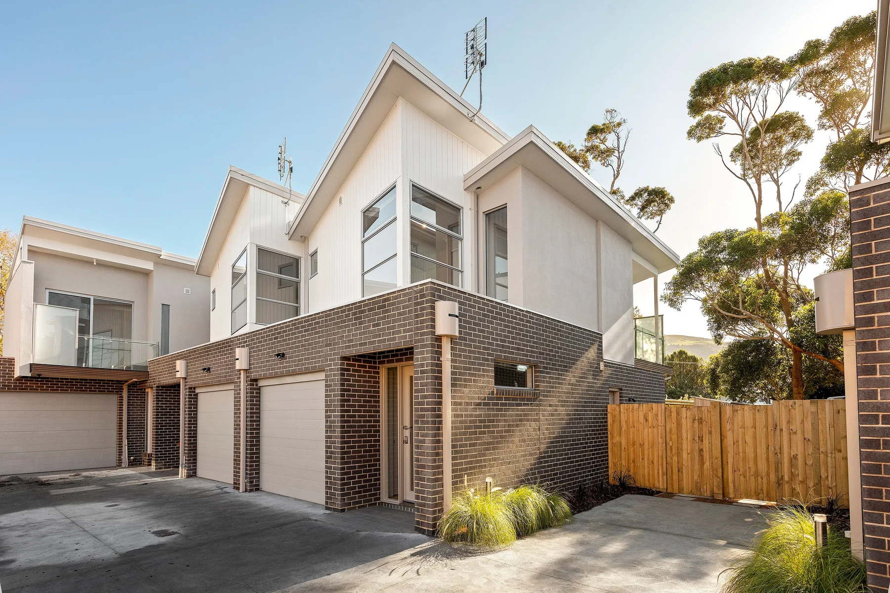 Modern multi-level house with brick exterior walls and a paved driveway.