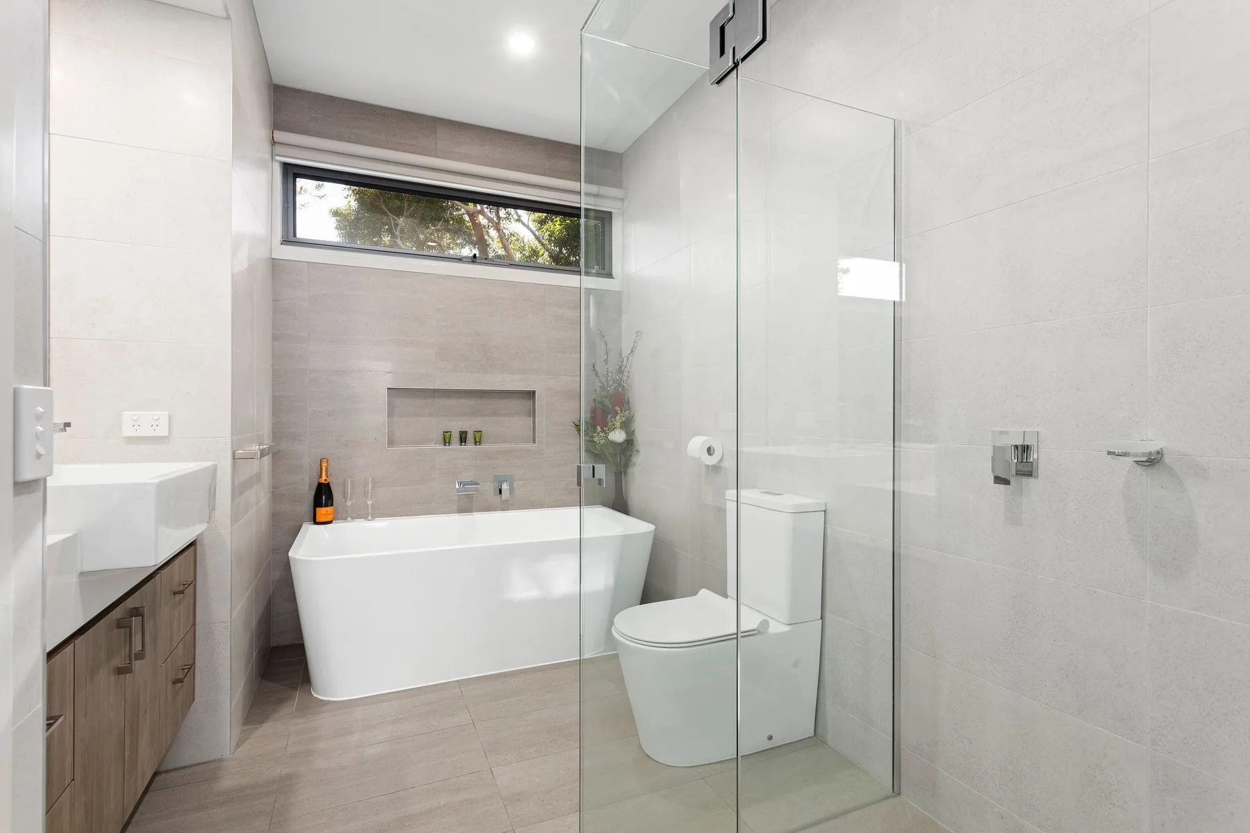 A modern bathroom with a bathtub, vanity, and glass shower.