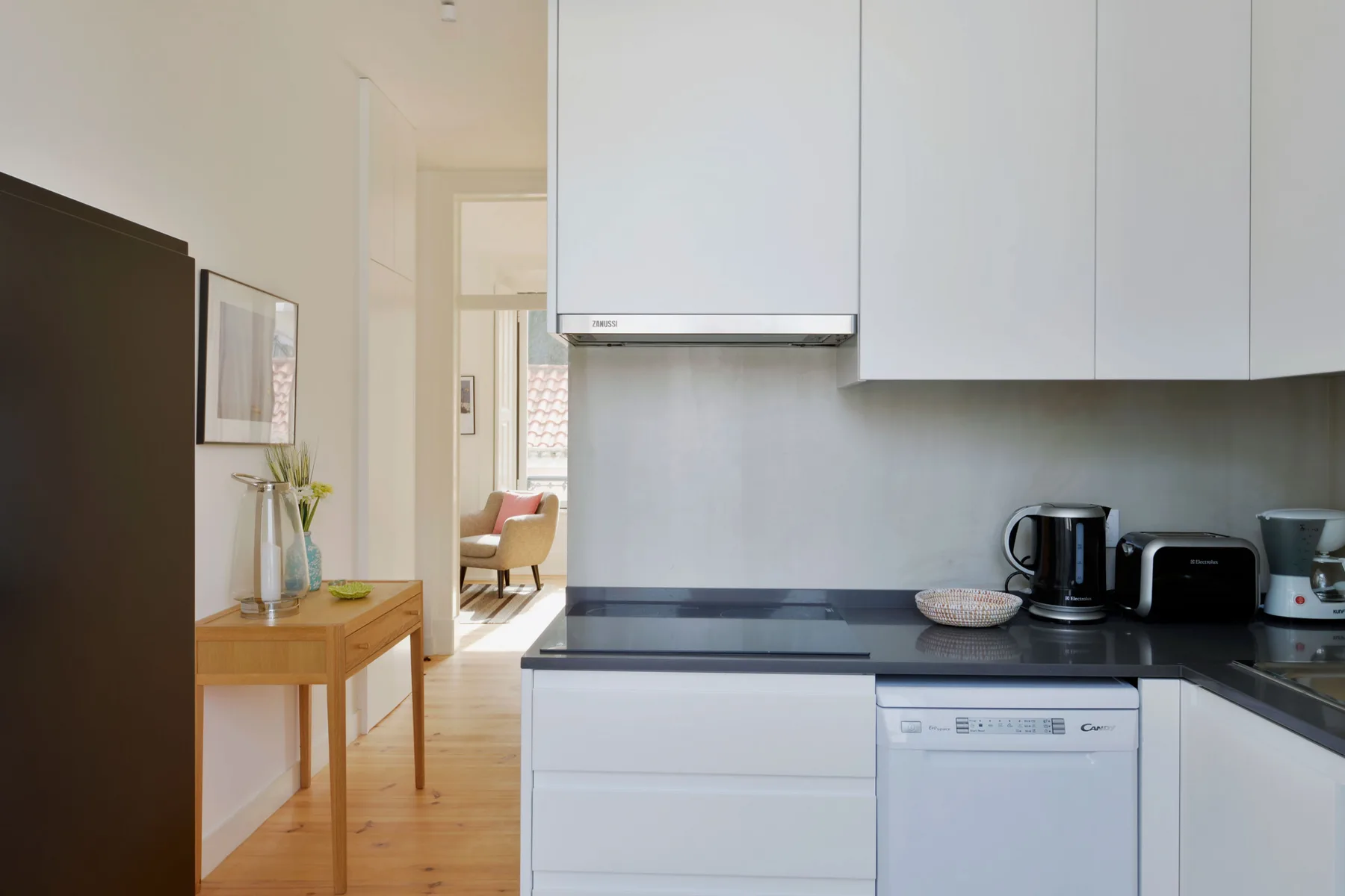 A bright kitchen with white cabinets and a counter beside a dining area.