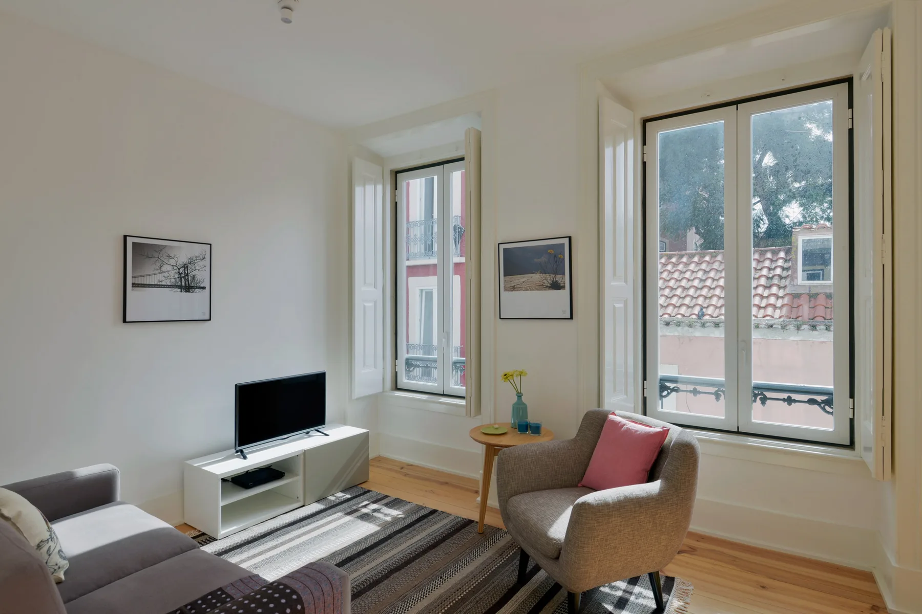 A living room with a television, seating, and large windows.
