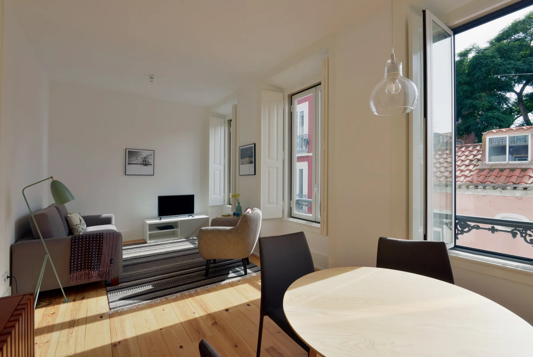 A bright living and dining area with seating, a television, and large windows.