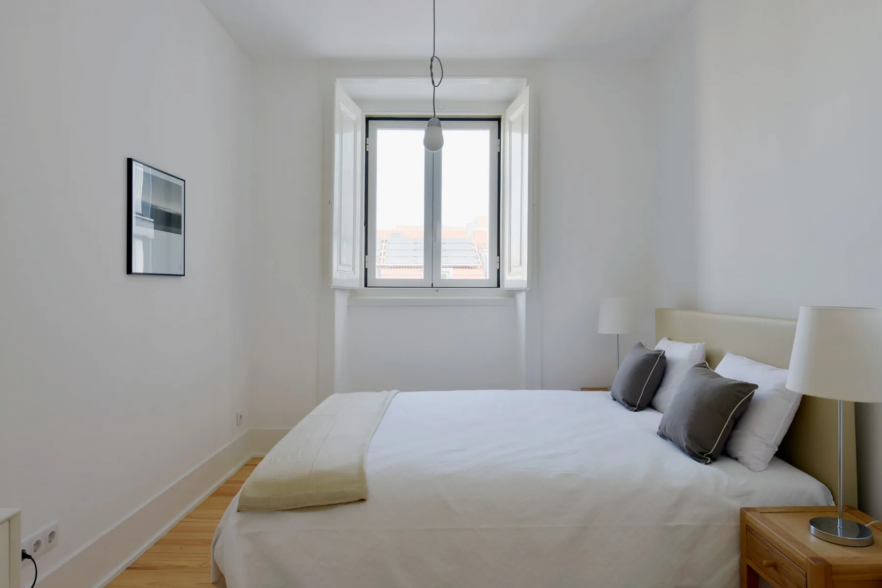A bright bedroom with a bed beneath a large window.