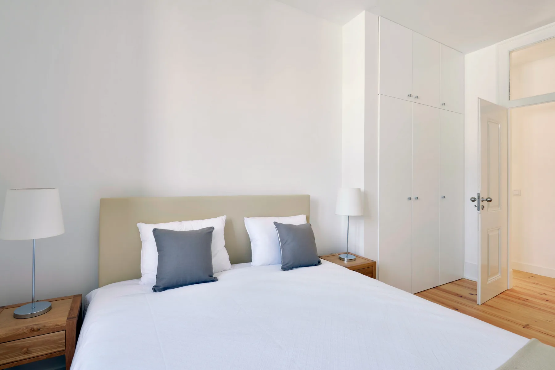A bright bedroom with a neatly made bed and built-in wardrobes.