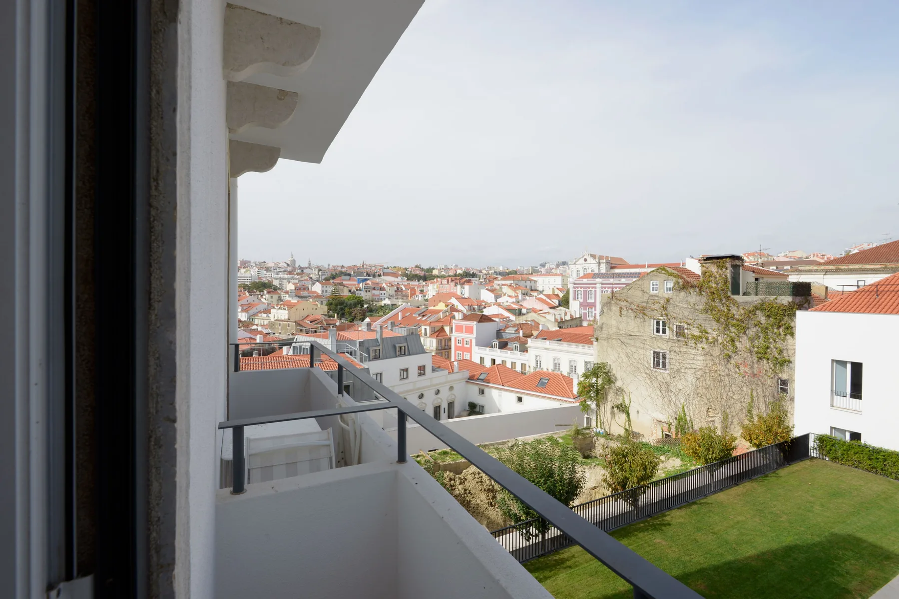 A balcony overlooks a cityscape of buildings with red-tiled roofs.