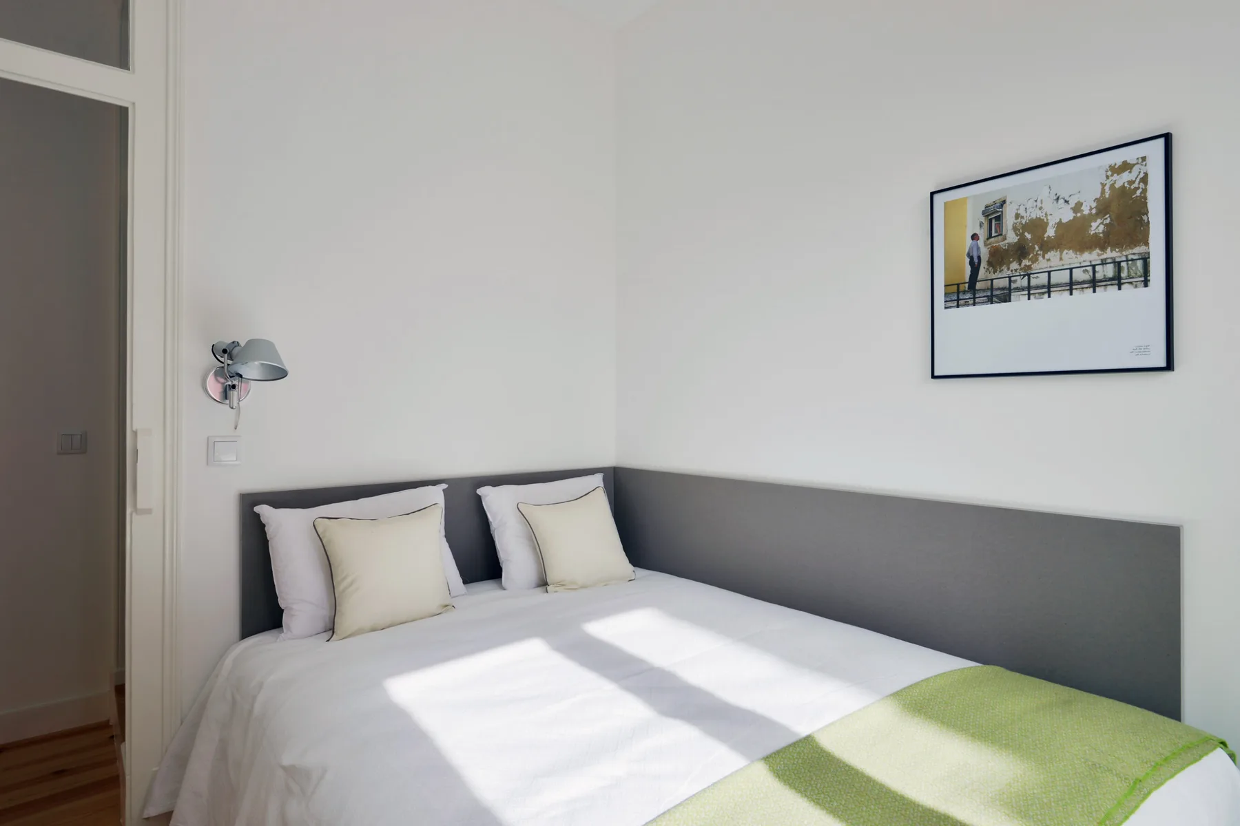 A bedroom with a neatly made bed and framed artwork on the wall.