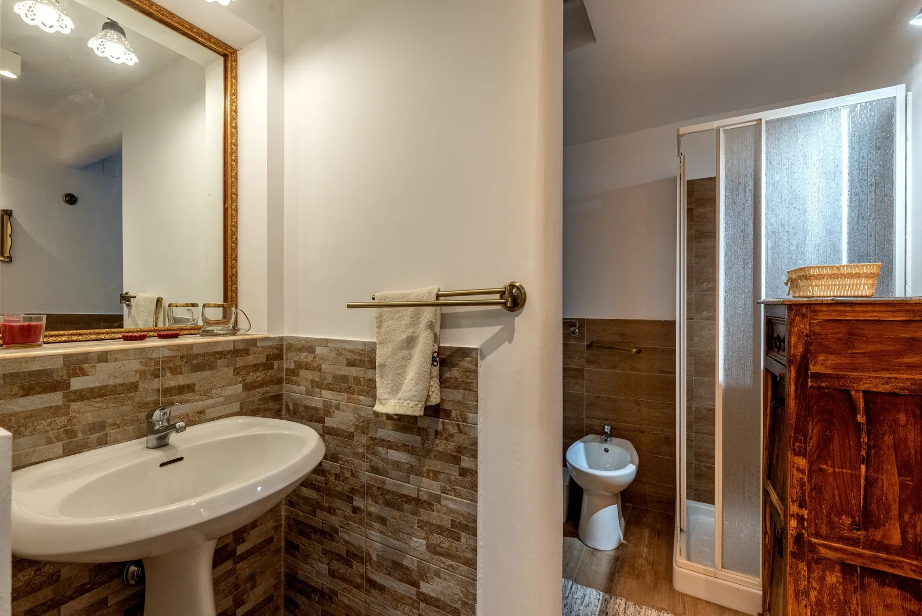 Un baño con lavabo de pedestal, paredes revestidas y una zona de ducha.