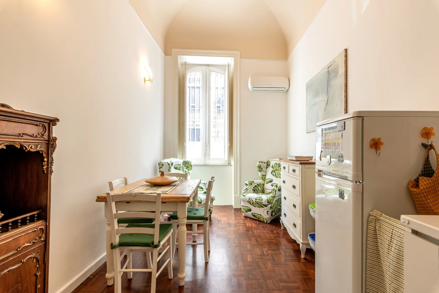 Un comedor luminoso con una mesa de madera y asientos tapizados en verde.