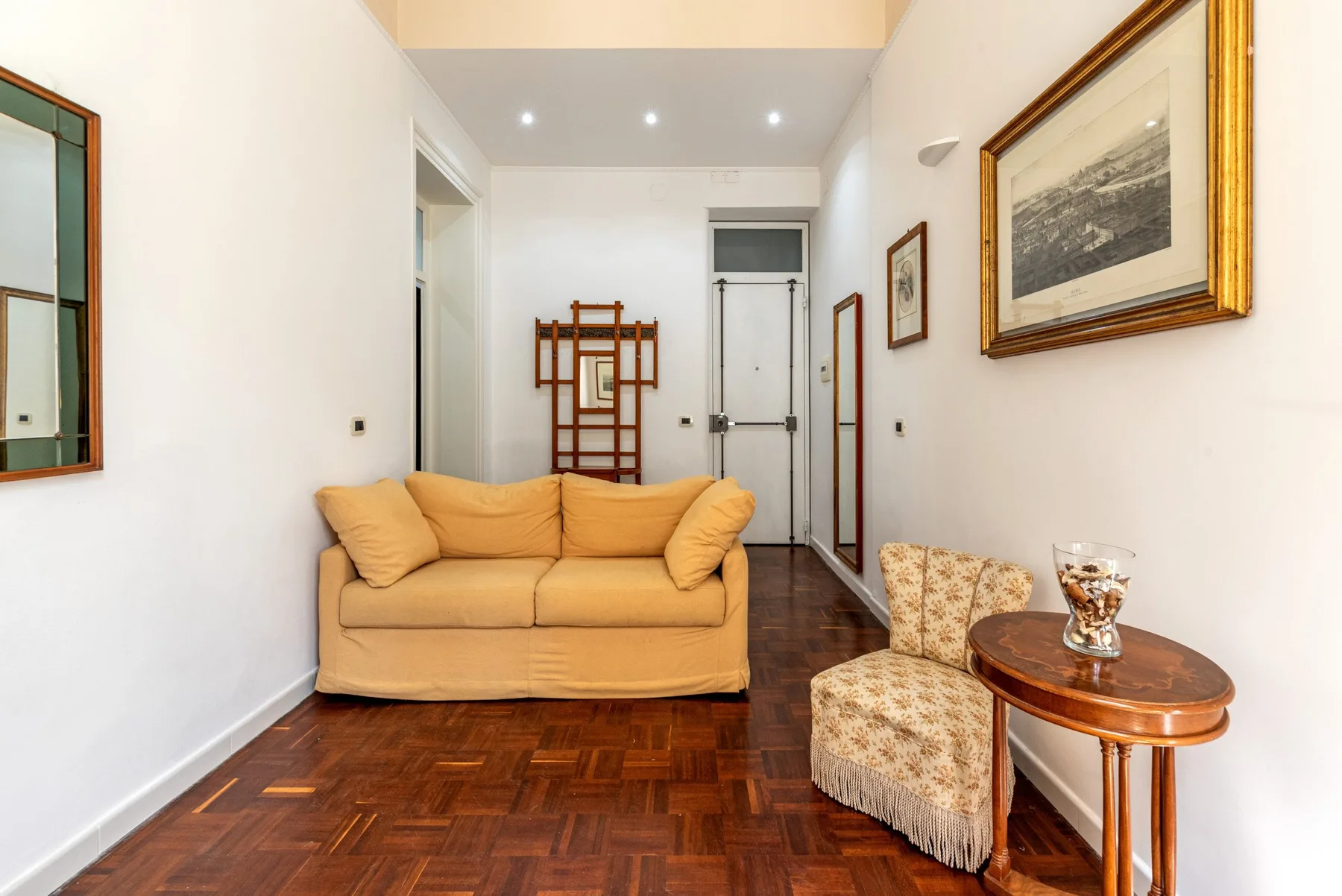Una sala de estar luminosa con un sofá color canela y cuadros enmarcados.