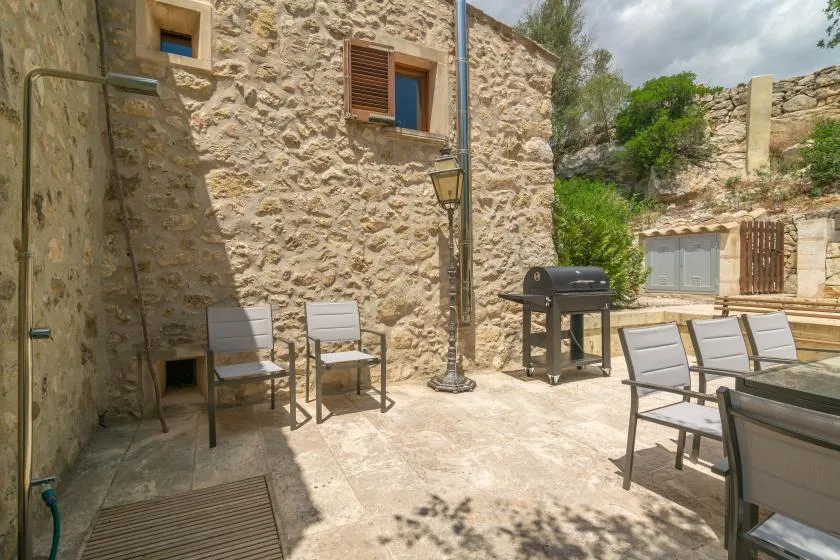 A stone courtyard with outdoor seating and a barbecue grill.
