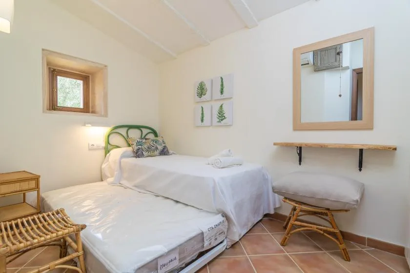A bedroom with two beds, a small window, and a wall-mounted shelf.