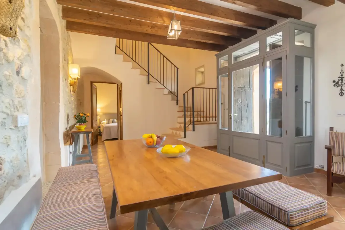 A dining area with a long wooden table beneath exposed ceiling beams.