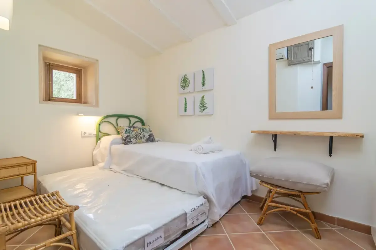 A bedroom with two beds, framed botanical prints, and a wall mirror.