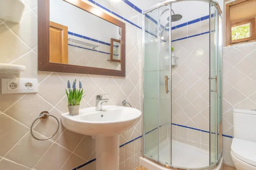 A tiled bathroom with a sink, mirror, and glass shower.