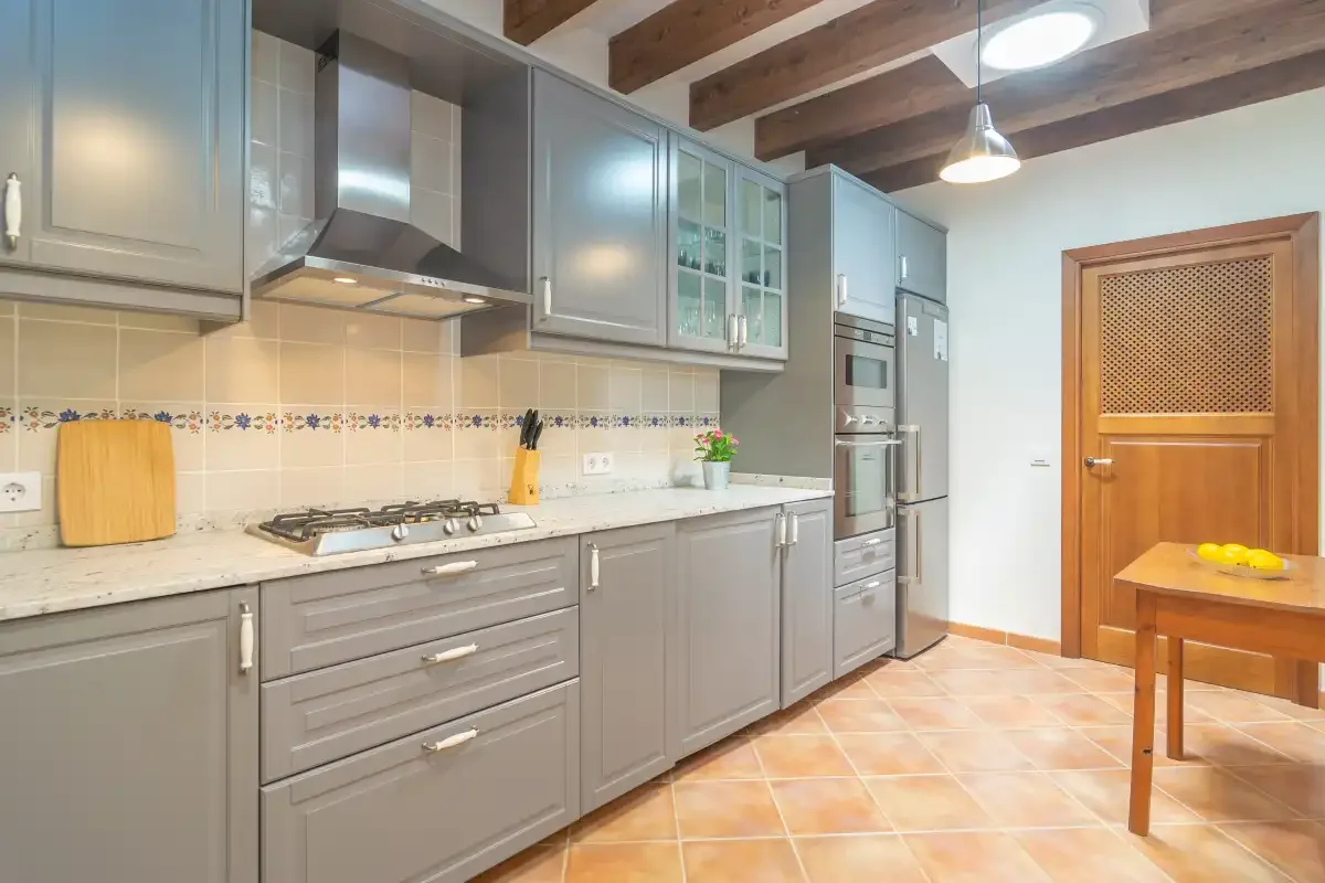 A modern kitchen with gray cabinets, a countertop, and a wooden dining table.