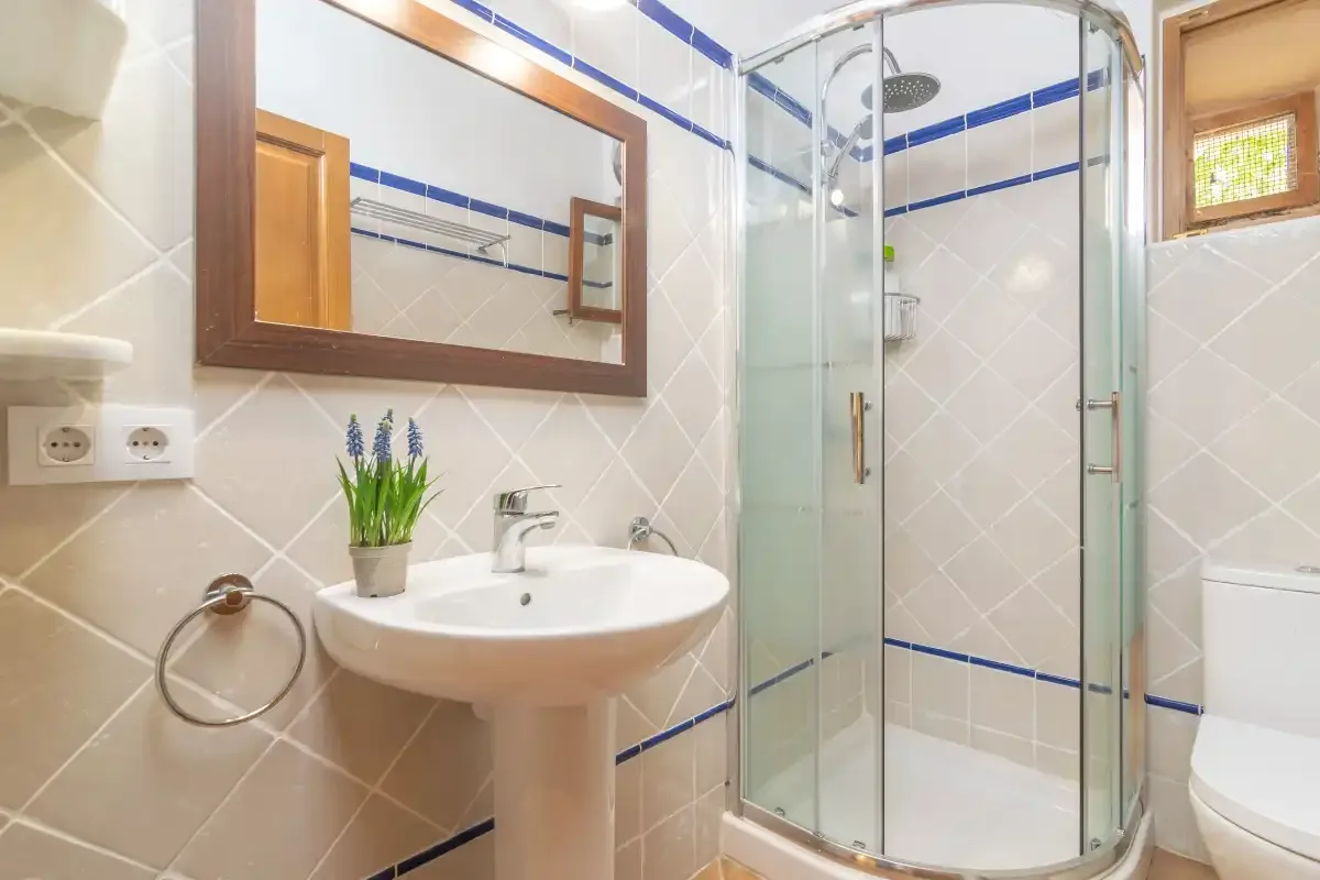 A tiled bathroom with a sink, mirror, and glass shower.