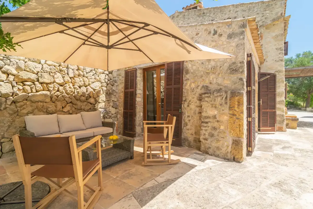 A stone patio with outdoor seating beneath a large umbrella.