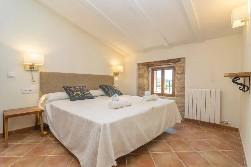 A bedroom with a neatly made bed and a small window.