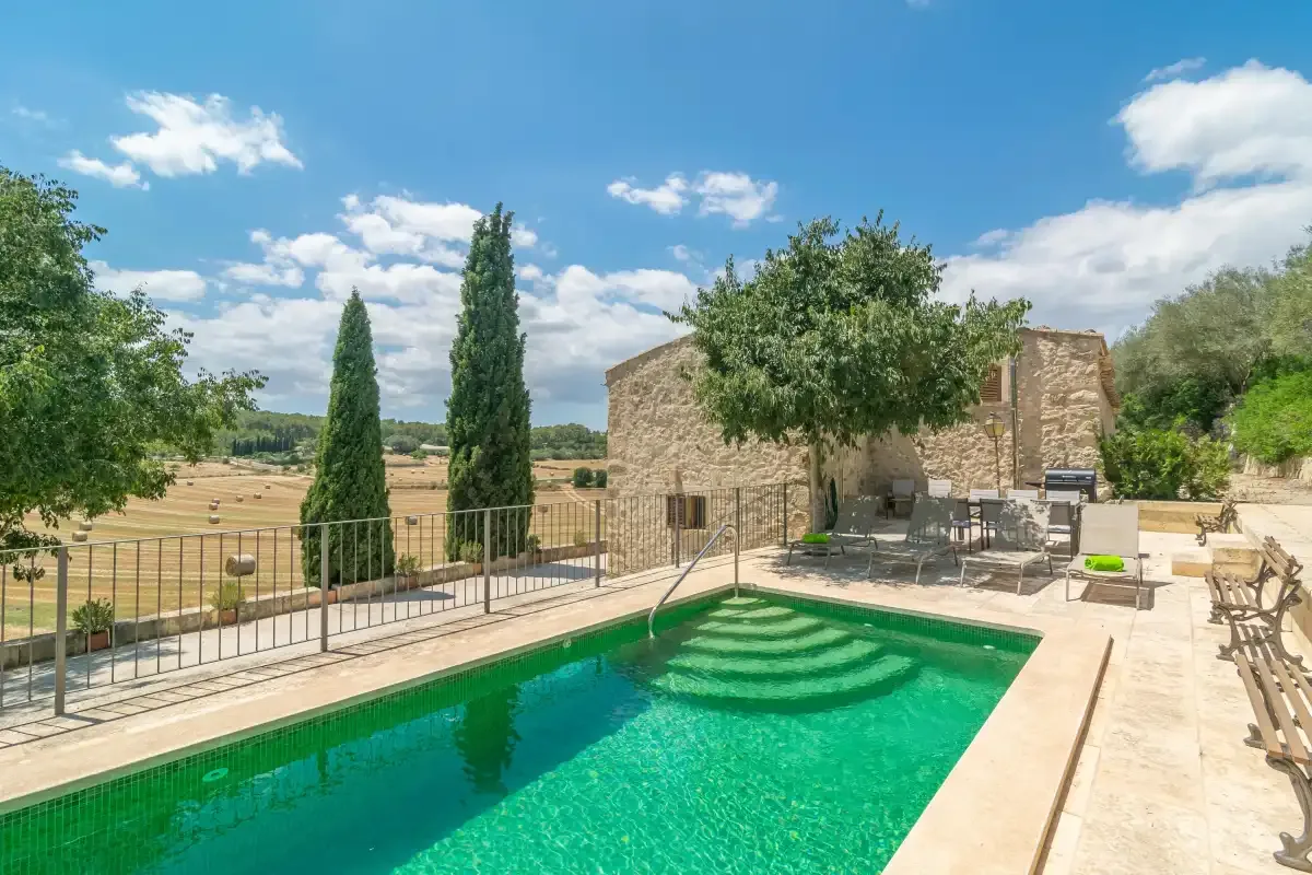 An outdoor swimming pool sits beside a stone building and patio seating.