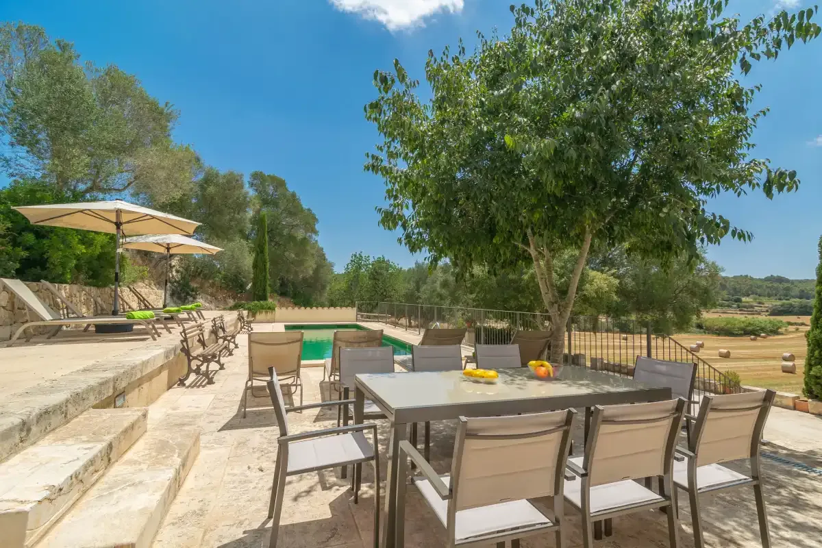 An outdoor dining area with a table and chairs beside a pool.