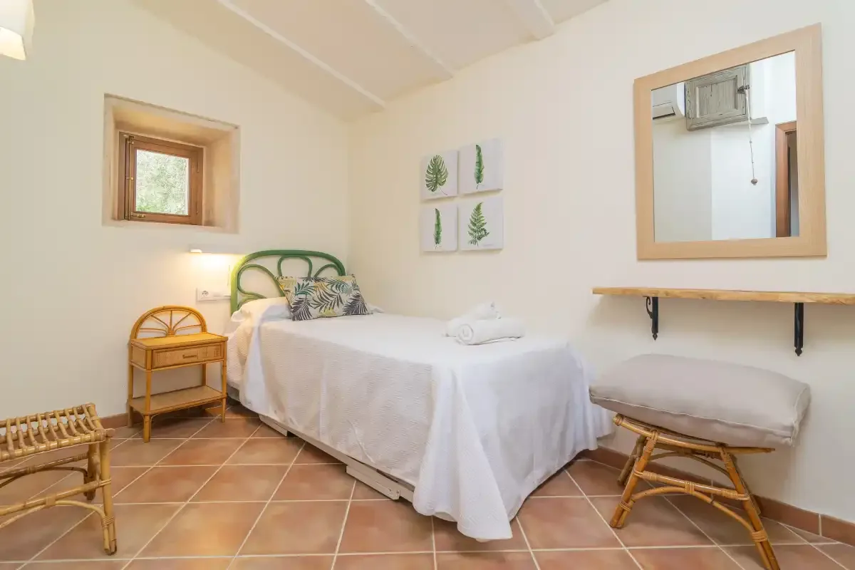 A bedroom with a neatly made bed, bedside table, and wall-mounted shelf.