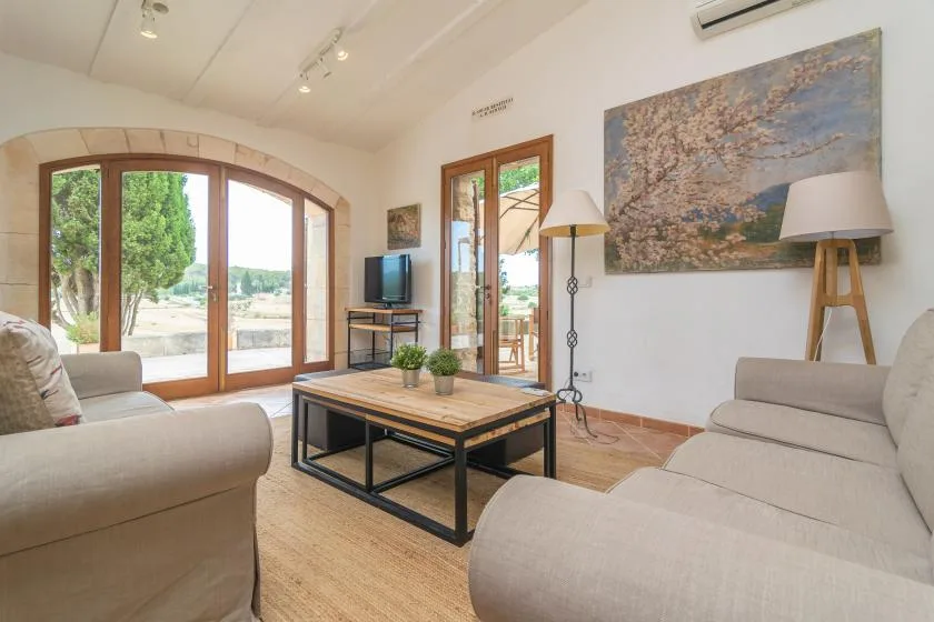 A bright living room with seating around a wooden coffee table and large windows.