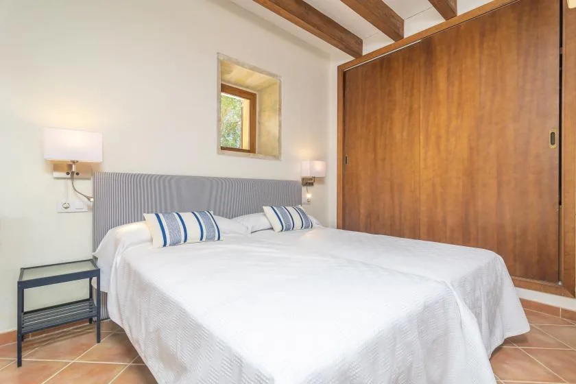 A bedroom with a bed, striped pillows, and a large wooden wardrobe.