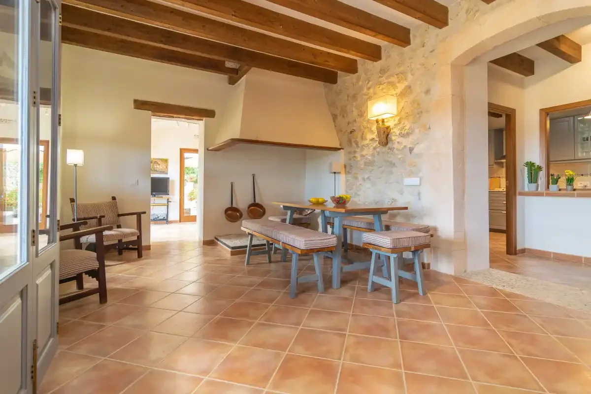 A rustic dining area with a wooden table and benches beneath exposed ceiling beams.
