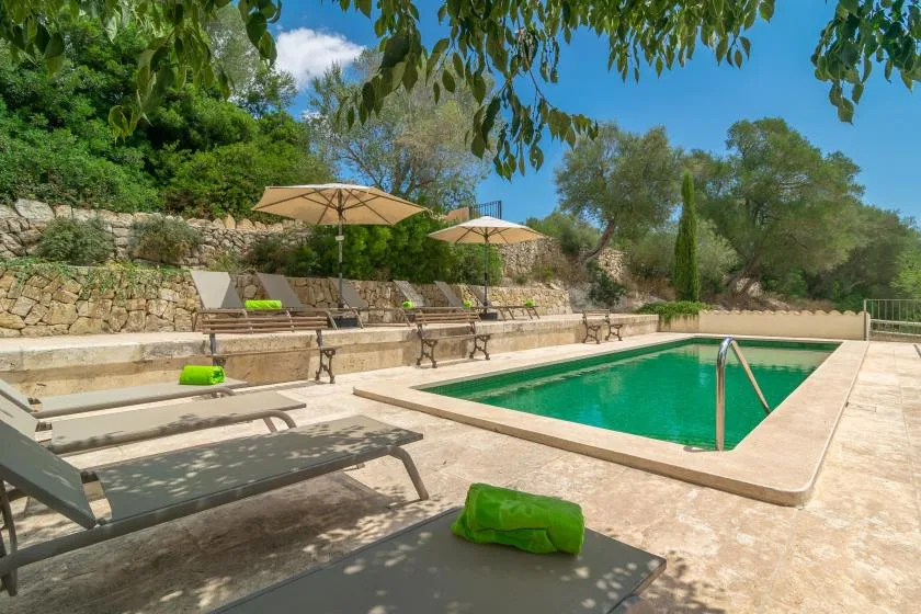 An outdoor swimming pool sits beside lounge seating and umbrellas.