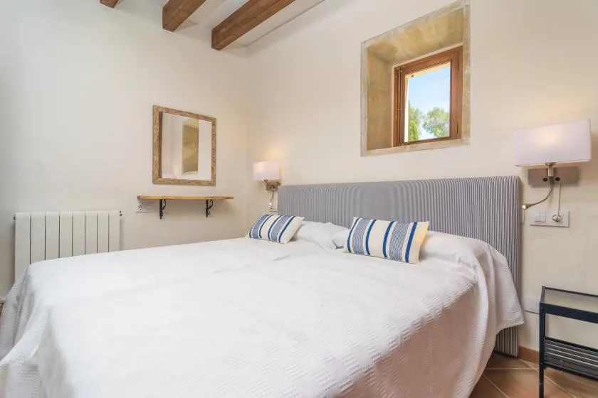 A bright bedroom with a large bed and a window above the headboard.