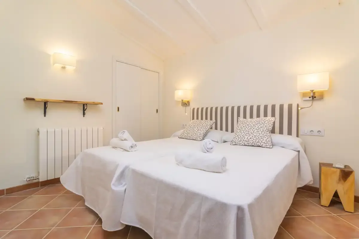 A bedroom with two beds, striped headboards, and white bedding.