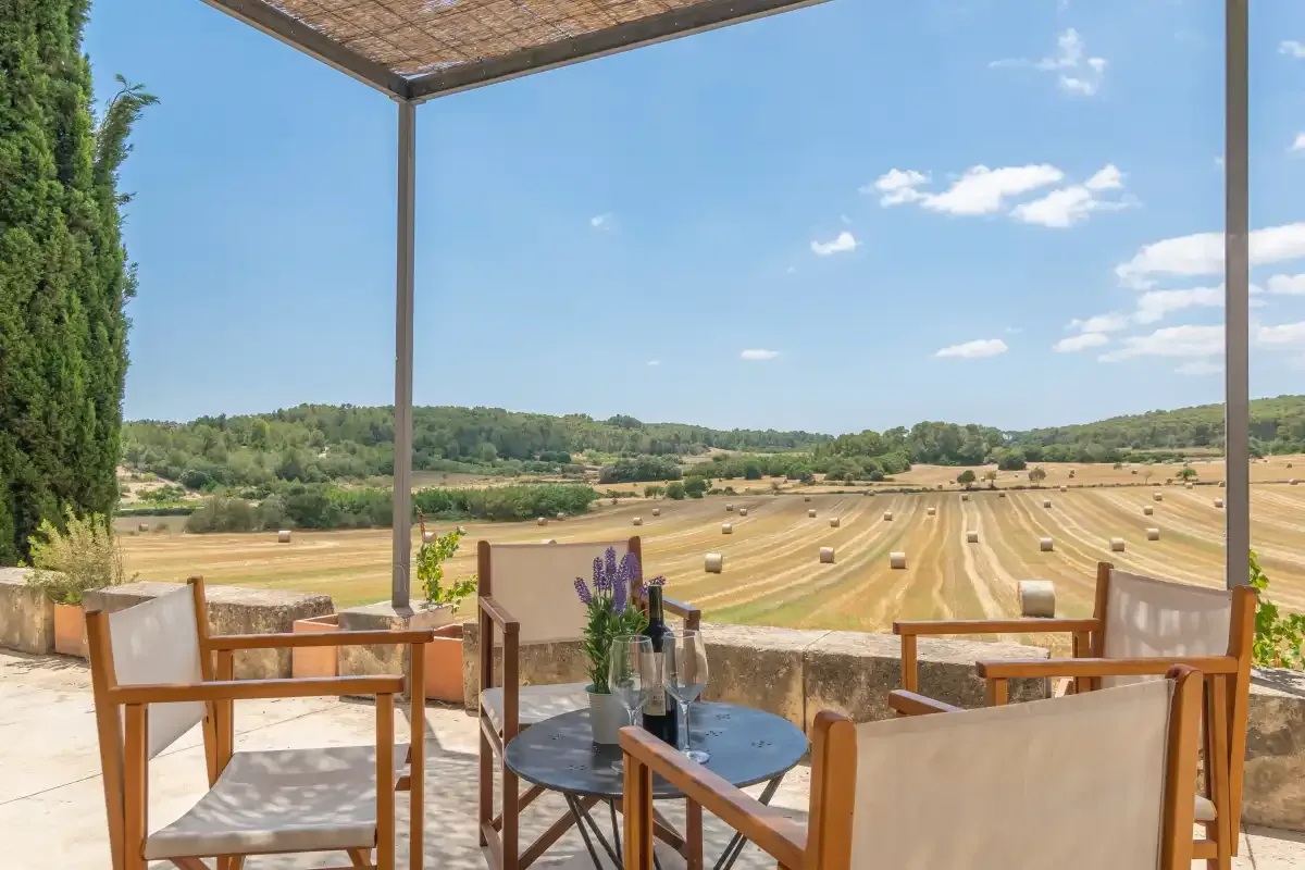 A covered terrace overlooks fields with round hay bales.