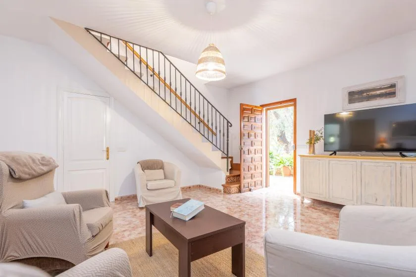 Una sala luminosa con asientos, una mesa de centro y una escalera.