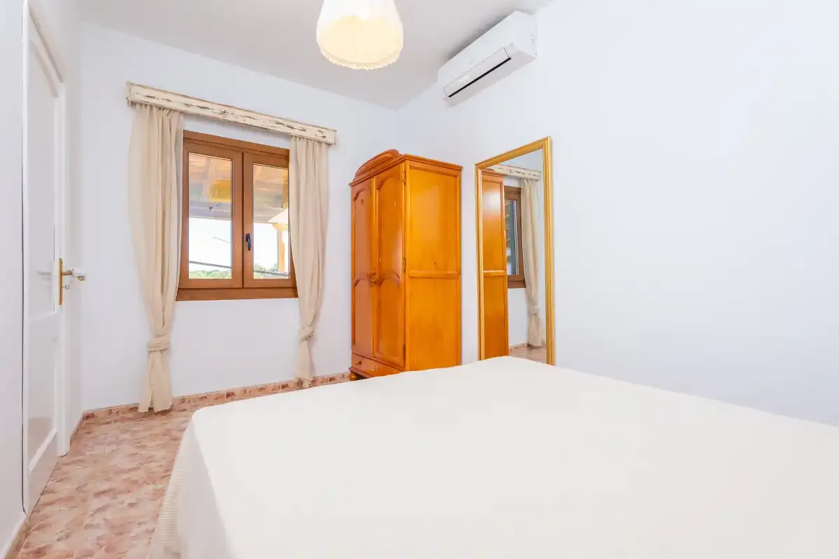 Un dormitorio con una cama, un armario de madera y una ventana.