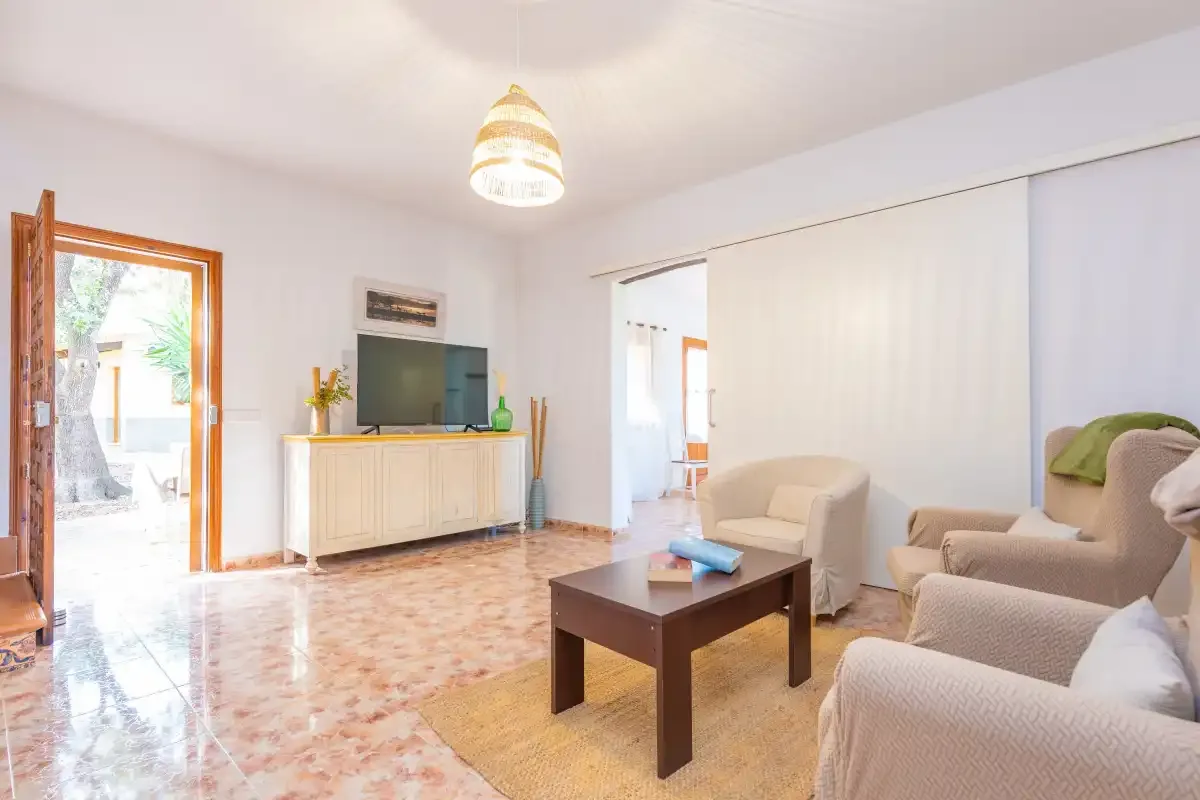 Una sala de estar luminosa con asientos, una mesa de centro y un televisor.