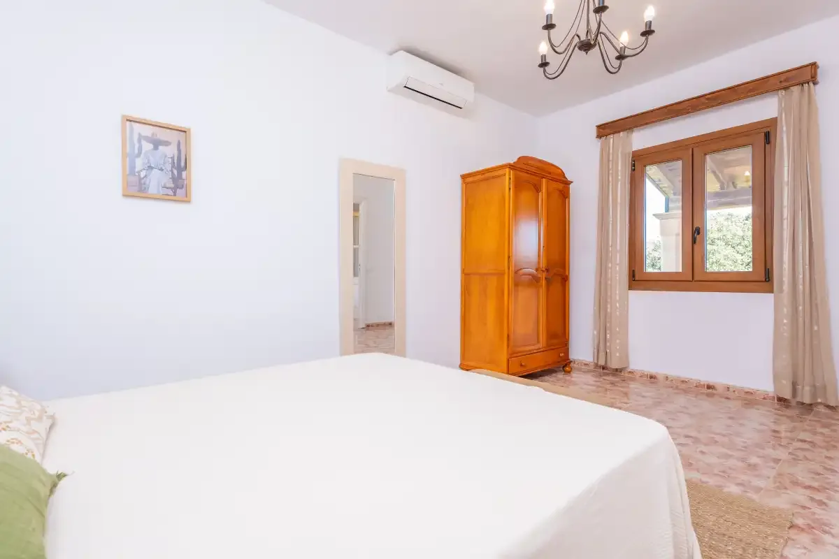 Un dormitorio con una cama, un armario de madera y una ventana.