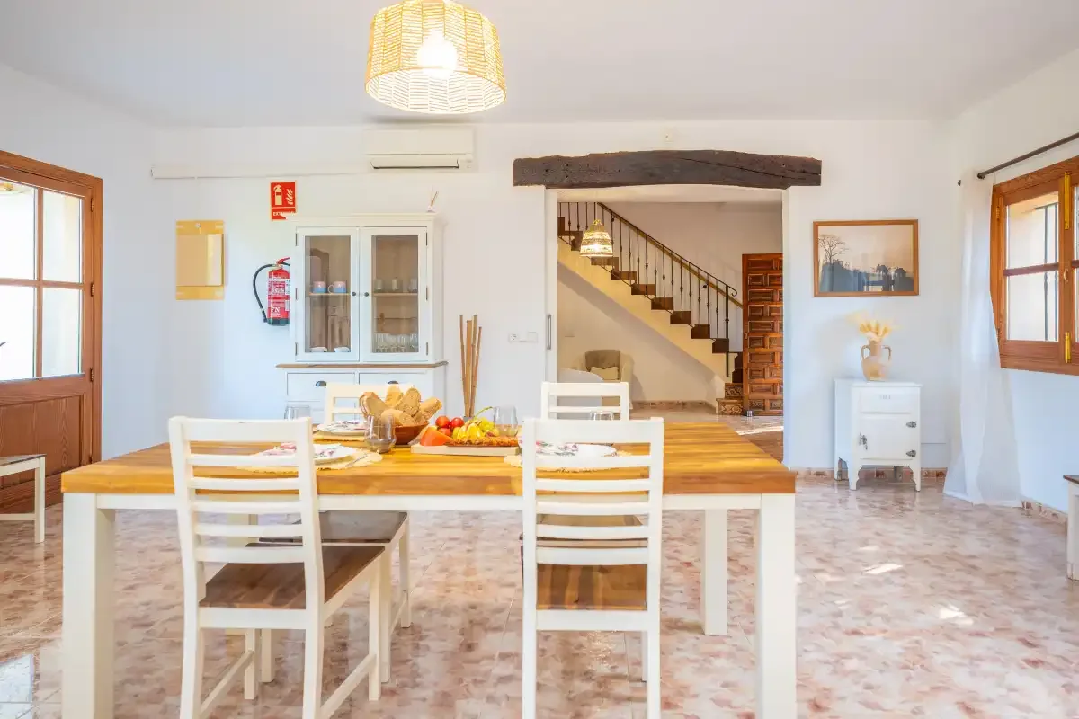 Un comedor con una mesa de madera y sillas está bajo una lámpara colgante.