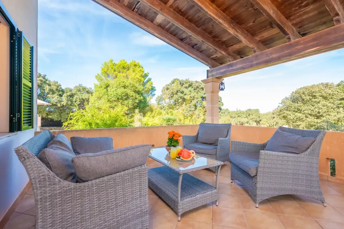Una zona de estar exterior cubierta con muebles de mimbre y una mesa baja.