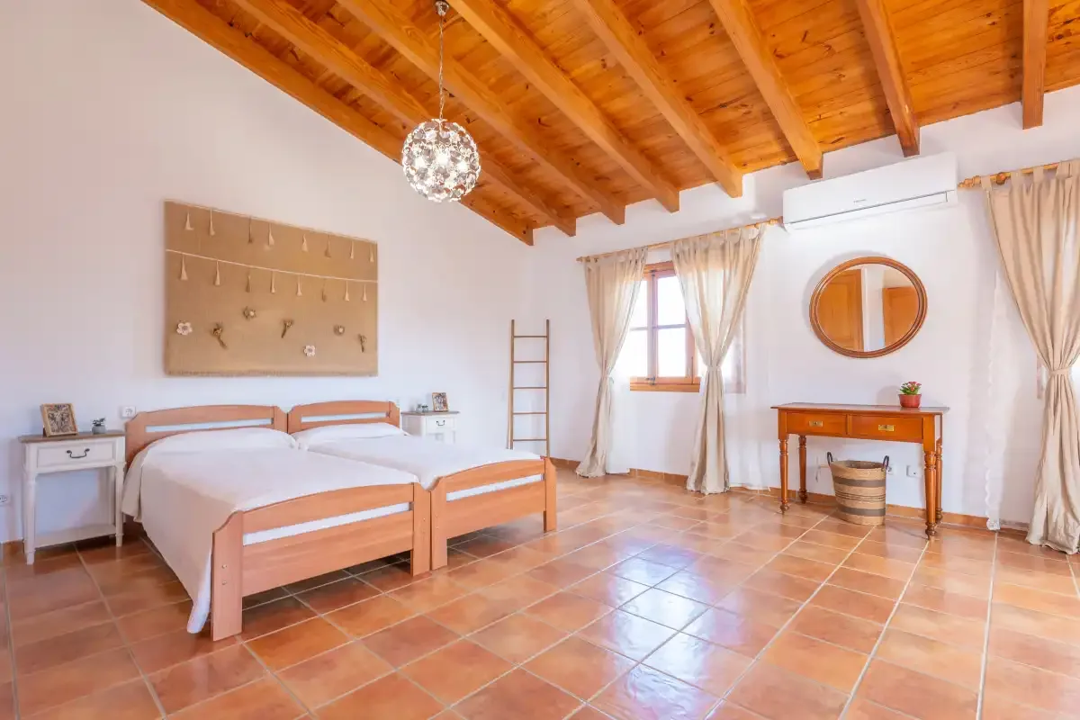 Dormitorio con dos camas, techo de madera y escritorio.