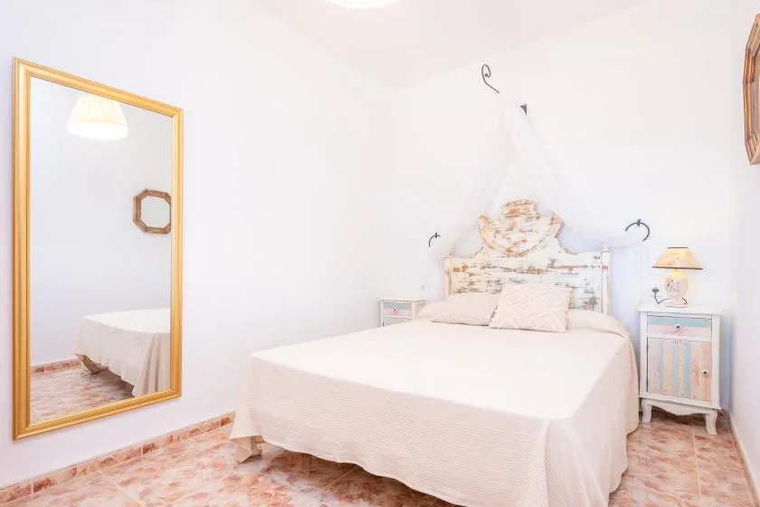 Un dormitorio luminoso con una cama, un espejo grande y una mesita de noche.